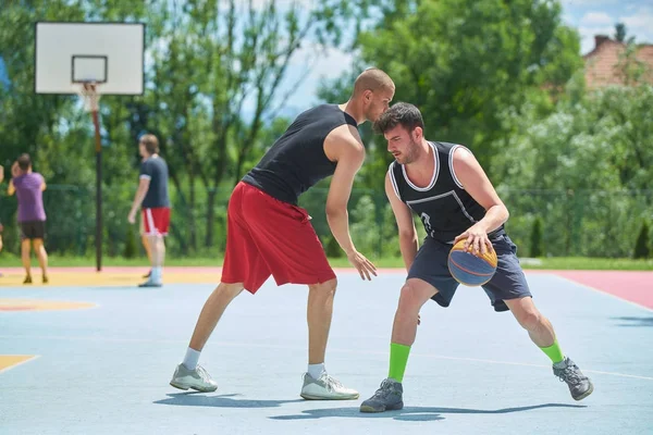 Couple of guys playing basketball outside
