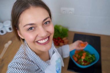 Genç kadın mutfakta taze sebze sepeti