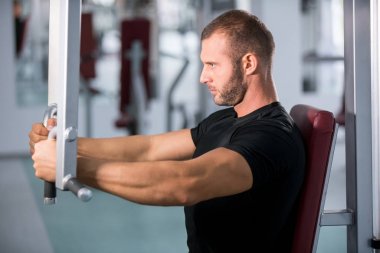 spor salonunda fitness makinede çalışan genç kaslı adam kararlı