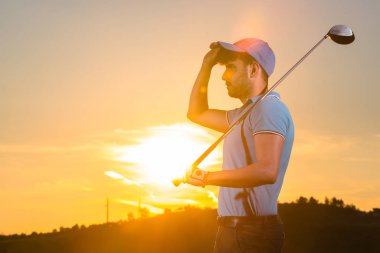 Adam günbatımı sırasında golf oynuyor