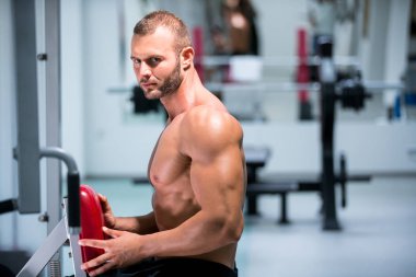spor salonunda fitness makinede çalışan genç kaslı adam kararlı