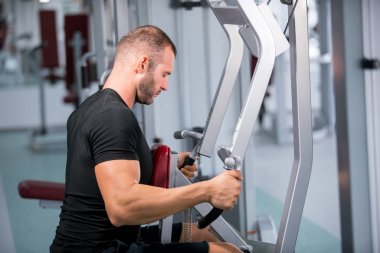 spor salonunda fitness makinede çalışan genç kaslı adam kararlı