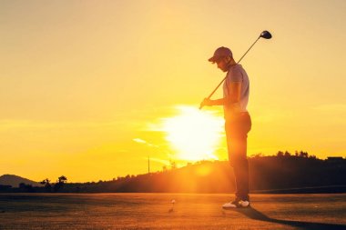 Adam günbatımı sırasında golf oynuyor