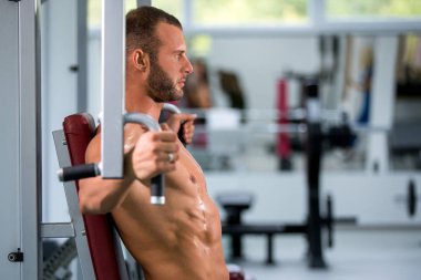 spor salonunda fitness makinede çalışan genç kaslı adam kararlı