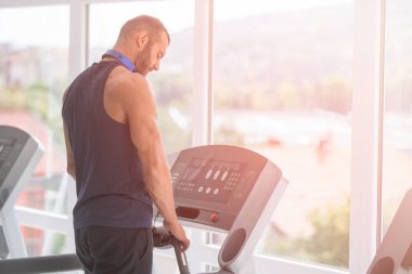 Spor giyimli genç adam spor salonunda koşu bandında koşuyor