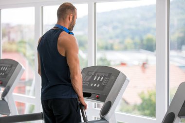 Spor giyimli genç adam spor salonunda koşu bandında koşuyor
