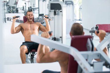 spor salonunda fitness makinede çalışan genç kaslı adam kararlı