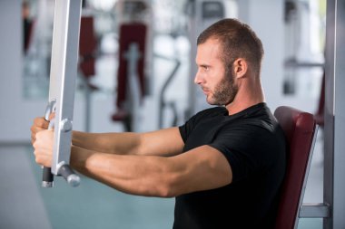 spor salonunda fitness makinede çalışan genç kaslı adam kararlı