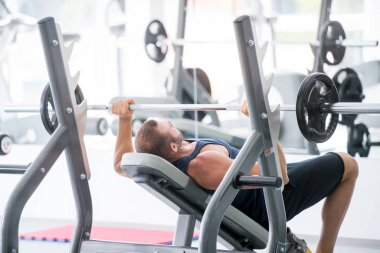 Spor, vücut geliştirme, yaşam tarzı ve insanlar kavramı - kasların esneme ve hamle spor salonunda basın omuz yapma barbell ile genç adam