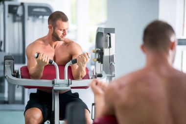 spor salonunda fitness makinede çalışan genç kaslı adam kararlı