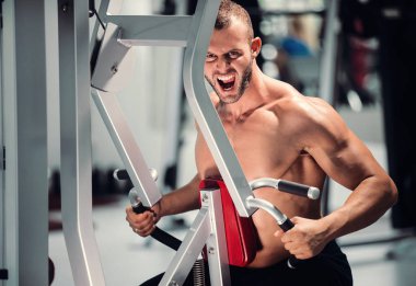 spor salonunda fitness makinede çalışan genç kaslı adam kararlı