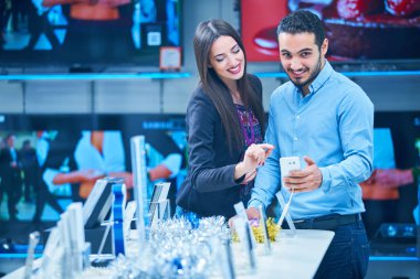 tüketici elektroniği genç bir çift satın almak en son dizüstü bilgisayar, televizyon ve fotoğraf kamera seyir saklamak