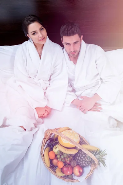 夫妇放松在床与果子篮子 — 图库照片