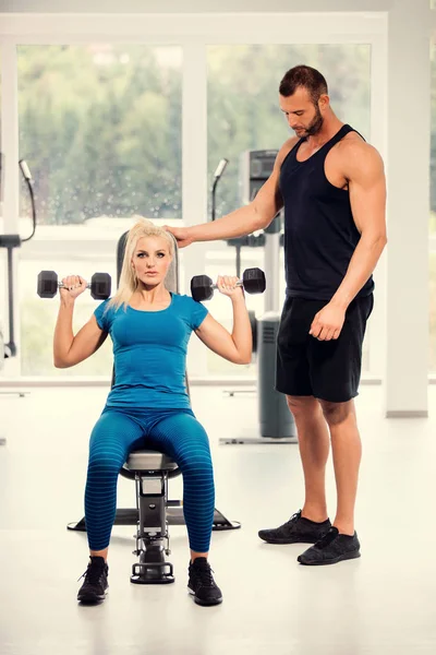 personal trainer working with young woman in the gym - Stock Image ...