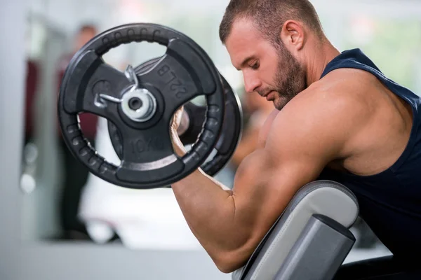 sport, bodybuilding, lifestyle and people concept - young man with barbell flexing muscles and making shoulder press lunge in gym