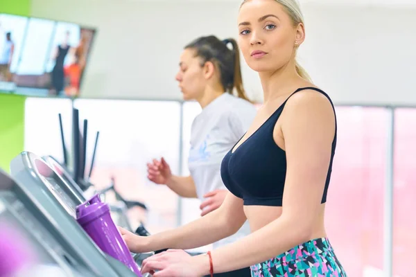 Girl runs on treadmill. Active girl in gym runs on treadmill. Athlete cardio activity on treadmill.