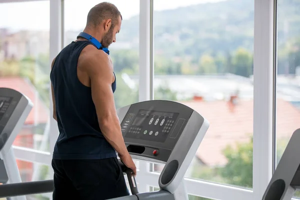 Young man in sportswear running on treadmill at gym