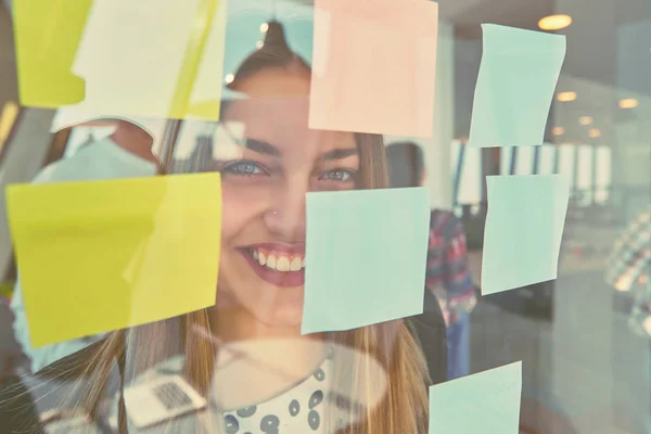 在现代办公室的办公室玻璃板上写在贴纸上的快乐创意女性 — 图库照片