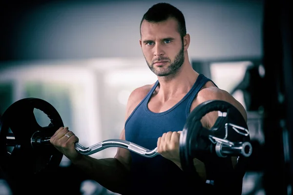 sport, bodybuilding, lifestyle and people concept - young man with barbell flexing muscles and making shoulder press lunge in gym