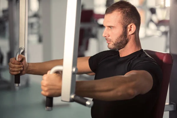 Determinado Jovem Homem Muscular Trabalhando Máquina Fitness Ginásio — Fotografia de Stock