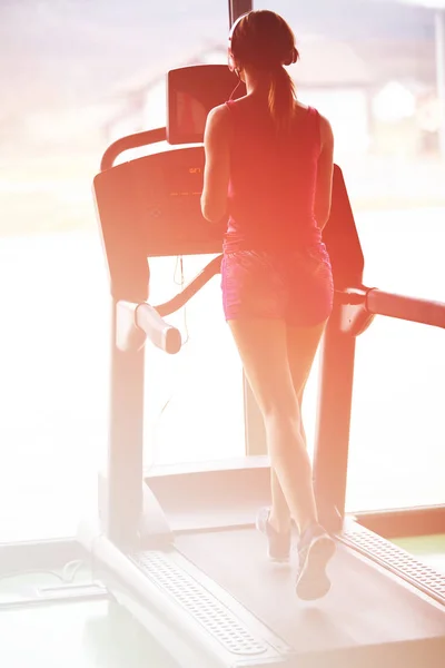 Girl runs on treadmill. Active girl in gym runs on treadmill. Athlete cardio activity on treadmill.