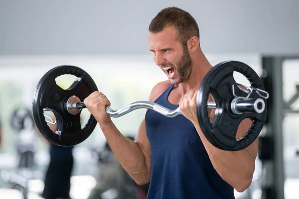sport, bodybuilding, lifestyle and people concept - young man with barbell flexing muscles and making shoulder press lunge in gym