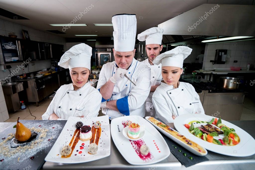 Kitchen chef with young apprentices making deserts