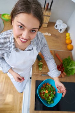 Genç kadın mutfakta taze sebze sepeti