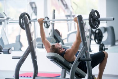 Spor, vücut geliştirme, yaşam tarzı ve insanlar kavramı - kasların esneme ve hamle spor salonunda basın omuz yapma barbell ile genç adam