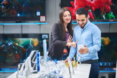 tüketici elektroniği genç bir çift satın almak en son dizüstü bilgisayar, televizyon ve fotoğraf kamera seyir saklamak
