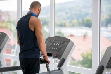 Spor giyimli genç adam spor salonunda koşu bandında koşuyor
