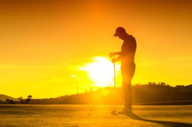 Adam günbatımı sırasında golf oynuyor