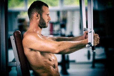 spor salonunda fitness makinede çalışan genç kaslı adam kararlı