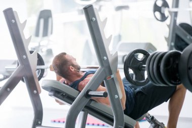 Spor, vücut geliştirme, yaşam tarzı ve insanlar kavramı - kasların esneme ve hamle spor salonunda basın omuz yapma barbell ile genç adam