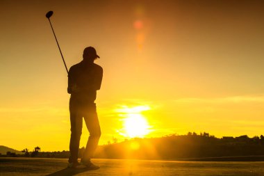 Adam günbatımı sırasında golf oynuyor