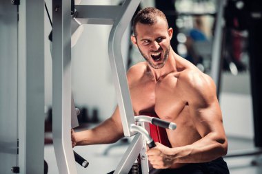 spor salonunda fitness makinede çalışan genç kaslı adam kararlı