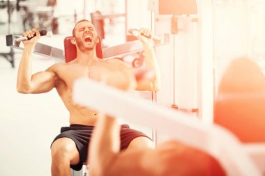 spor salonunda fitness makinede çalışan genç kaslı adam kararlı