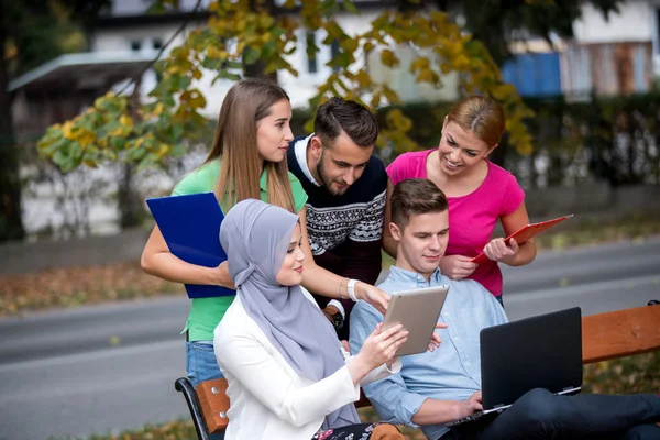Группа Молодых Людей Использующих Ноутбук Планшет Скамейке Парке Веселятся Разговаривают — стоковое фото