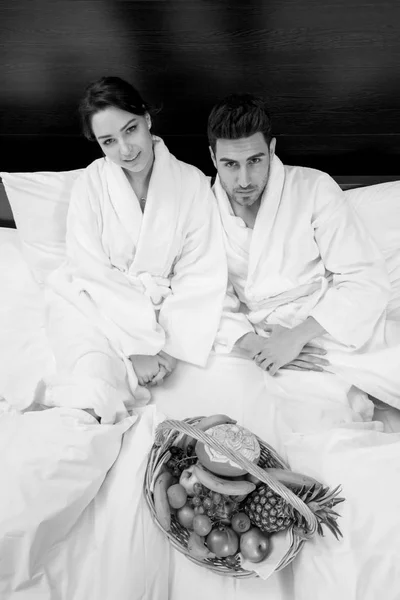 Couple relaxant au lit avec panier de fruits — Photo