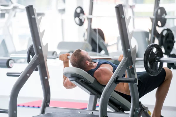 Spor, vücut geliştirme, yaşam tarzı ve insanlar kavramı - kasların esneme ve hamle spor salonunda basın omuz yapma barbell ile genç adam