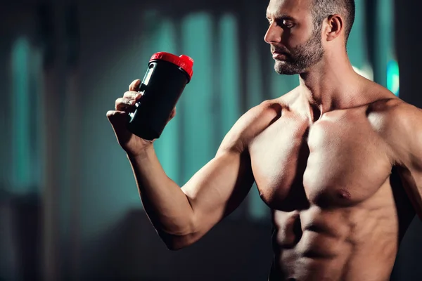 handsome young muscular man drinks a protein in the gym