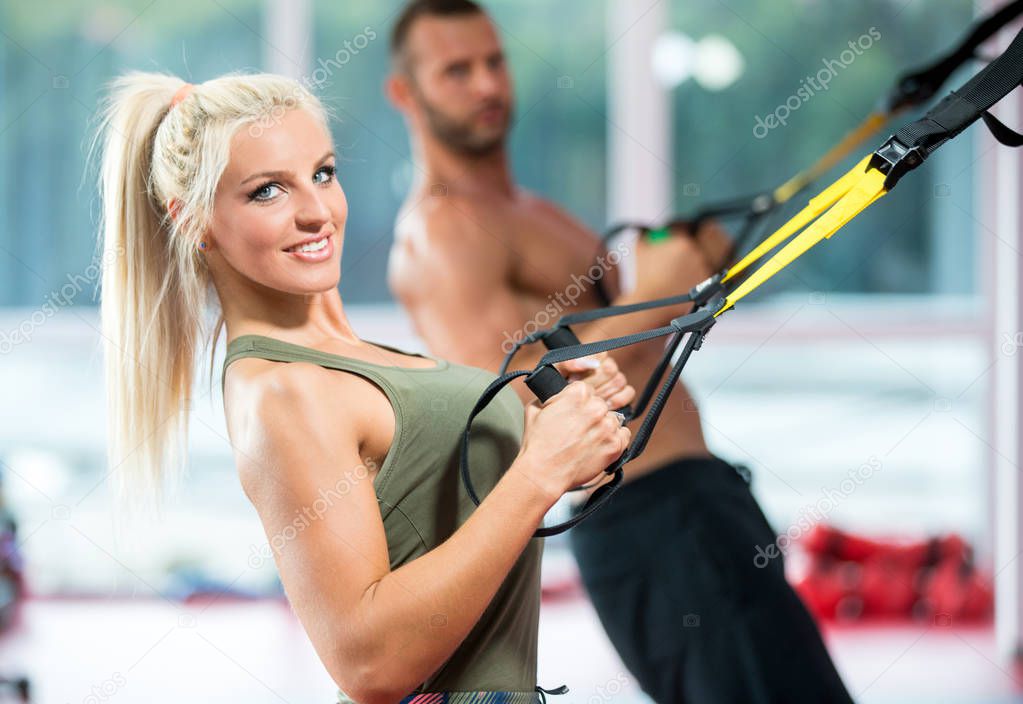 couple doing push ups training arms with trx fitness straps in the gym Concept workout healthy lifestyle sport