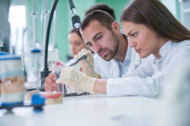 Takma diş, ağız hijyeni. Takma diş, takma diş, bir çalışma ve diş araçları içeren bir tablo üzerinde çalışırken protez eller.