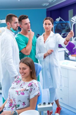 Diş hekimi diş bir hastanın röntgeni modern ofisinde gösterir.