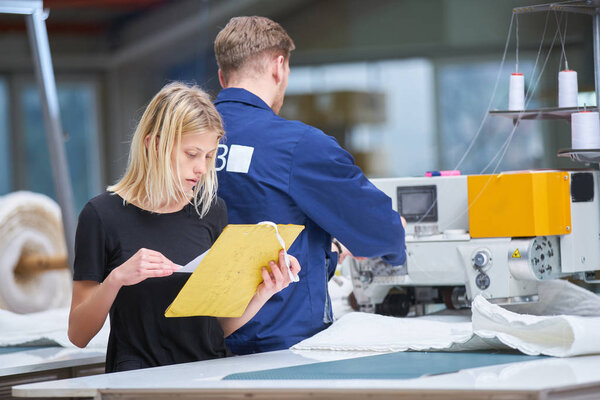 Seamstress is new assigned to a machine in a textile factory, the foreman explains something