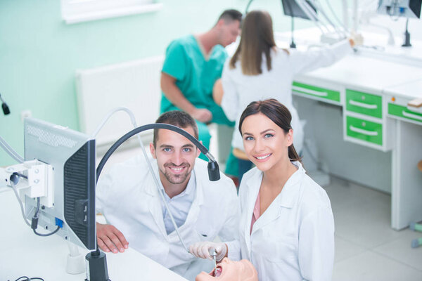 Dentures, oral hygiene. Prosthetics hands while working on the denture, false teeth, a study and a table with dental tools.