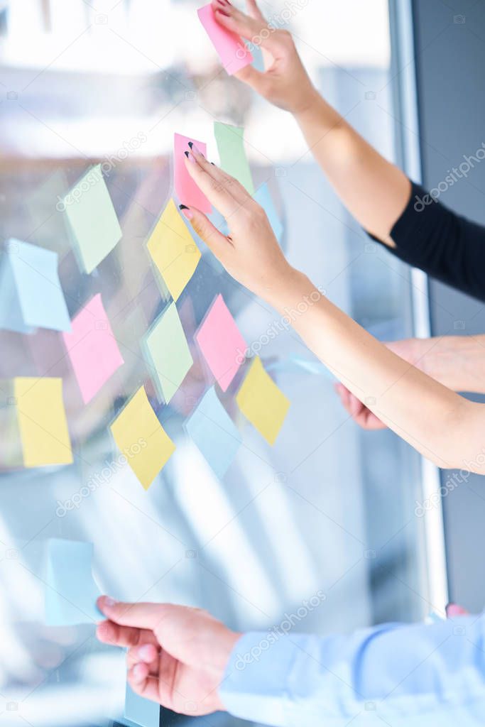 business, startup, planning, management and people concept - happy creative team writing on stickers at office glass board