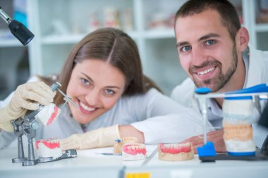 Takma diş, ağız hijyeni. Takma diş, takma diş, bir çalışma ve diş araçları içeren bir tablo üzerinde çalışırken protez eller.