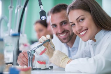 Takma diş, ağız hijyeni. Takma diş, takma diş, bir çalışma ve diş araçları içeren bir tablo üzerinde çalışırken protez eller.