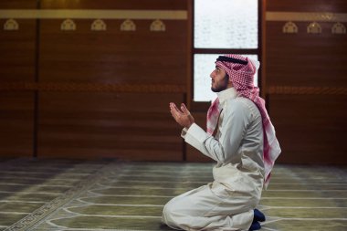 Dindar Müslüman adam caminin içinde dua ediyor.